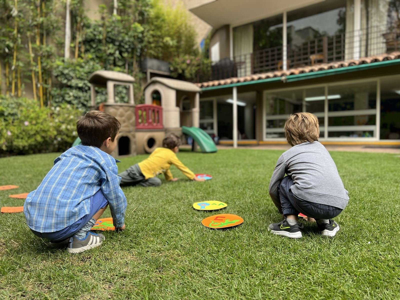 Two children playing a game on the school lawn, seen from behind